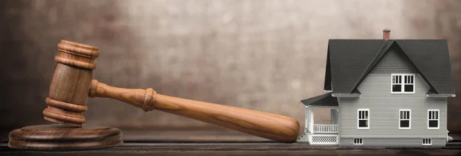 Auction hammer and gavel with a small model house in the background